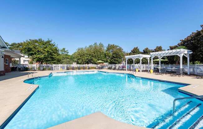 A large swimming pool with a white pergola in the background.