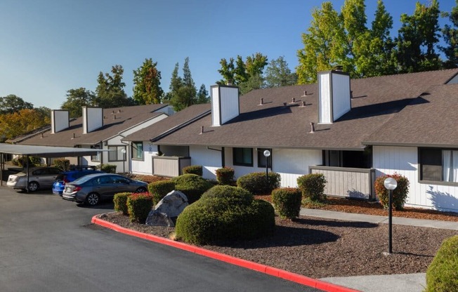 A parking lot in front of a building with a white fence and a red line painted on the ground.