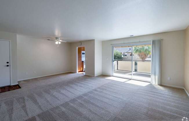 an empty living room with a sliding glass door to a patio