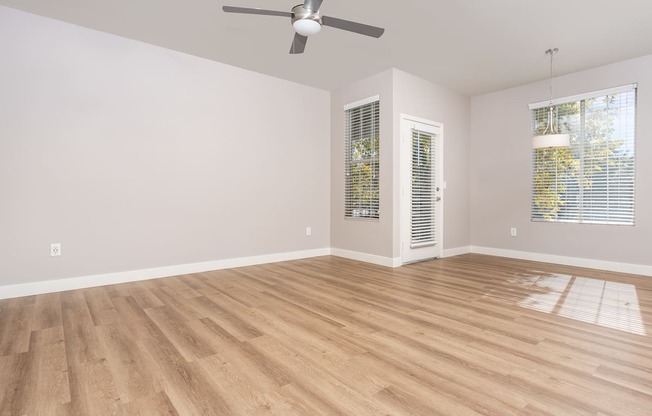 an empty living room with wood floors and a ceiling fan