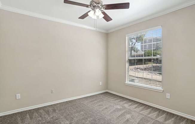 Edinburgh bedroom with a ceiling fan and a window at Encore at Buckingham Apartments in Richardson, TX