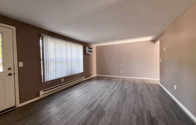 an empty living room with wood floors and a window