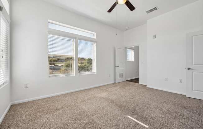 an empty living room with carpet and a ceiling fan