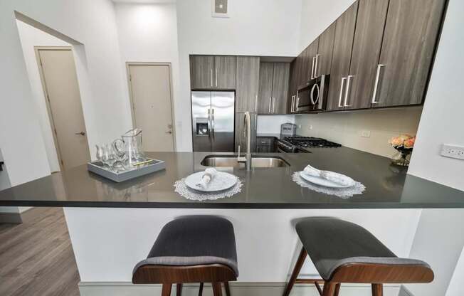 A kitchen with a black countertop and two chairs.