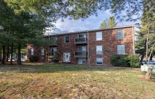 A brick apartment building with a green lawn in front.