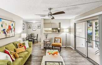 Model living room with a green couch and a sliding glass door leading to the patio at Hunters Chase in Austin, TX