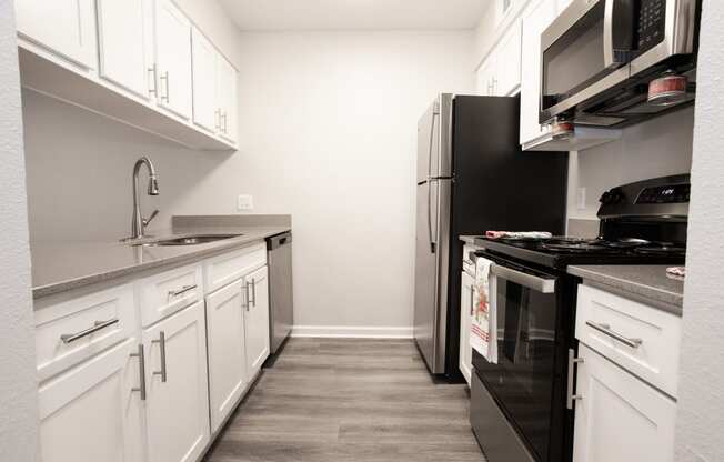 a kitchen with white cabinets and a black stove and refrigerator