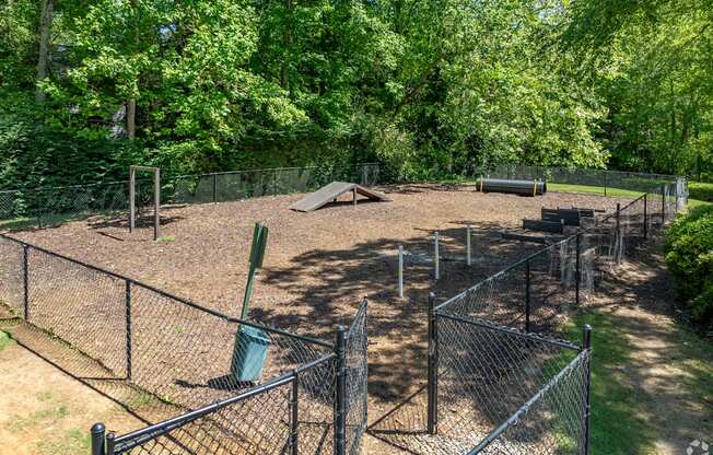 a fenced in dog park with a    and trees