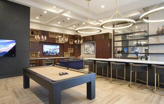 a pool table in a clubhouse with a bar and tv