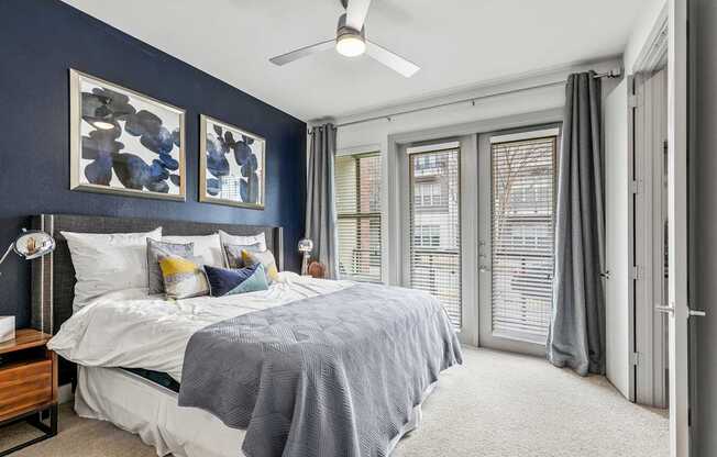 A bedroom with a bed, a ceiling fan, and a window with blinds.