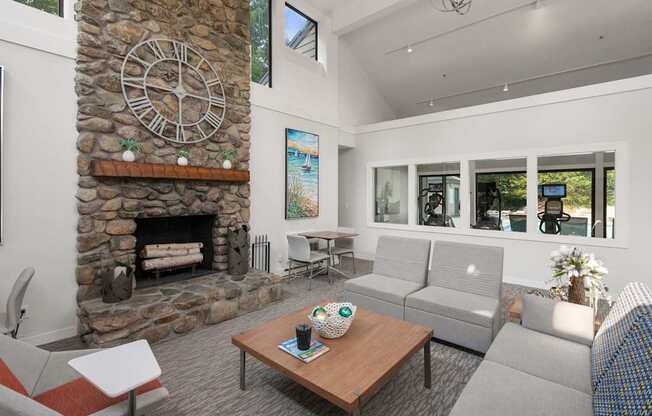A living room with a stone fireplace and a large clock on the wall.