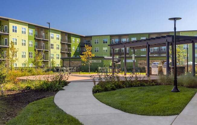 A walkway leads through a grassy area in front of apartment buildings.