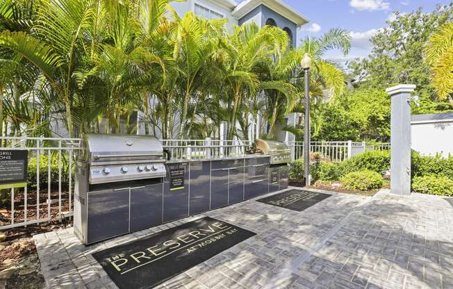 a barbecue grill in front of a house with palm trees