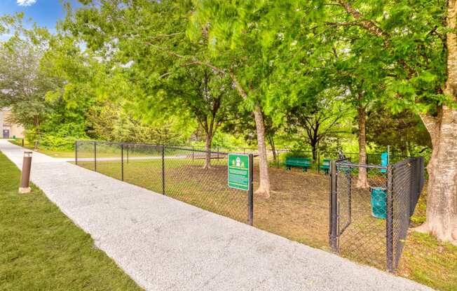 a park with a chain link fence and a sign for a dog park