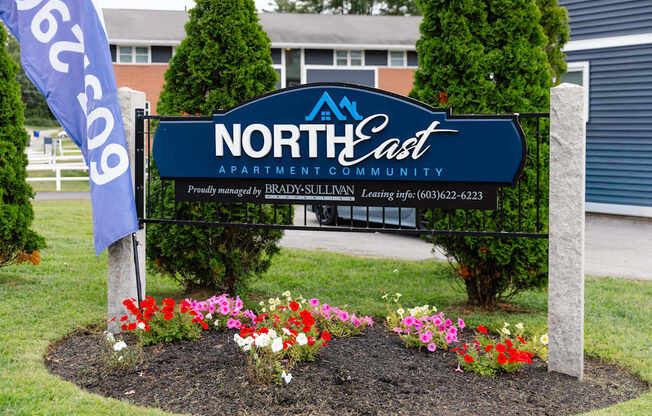 A sign for North East Apartment Community with a phone number on it.
