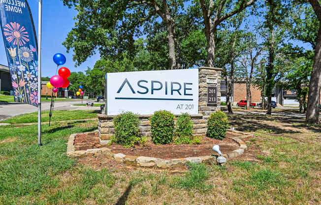 A sign that says "ASPIRE AT 201" is in front of a grassy area.