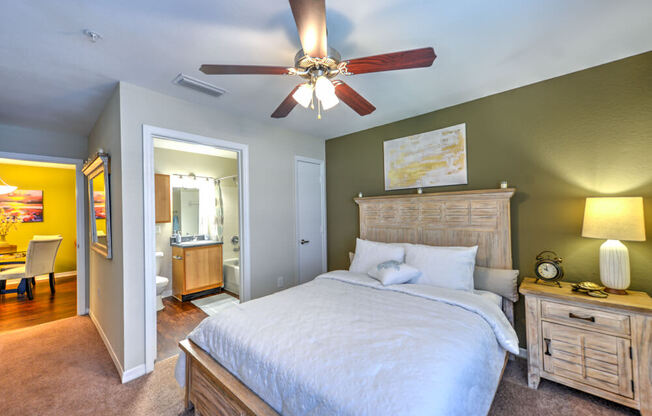 A bedroom with a bed, nightstand, and a ceiling fan.