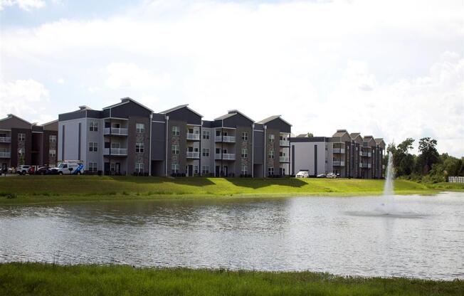 a pond with a fountain in front of an apartment building