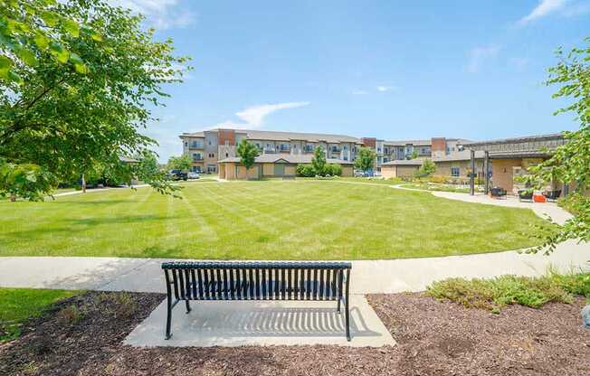 An expansive green courtyard lawn with a walking path around the edge, and a bench to rest on.