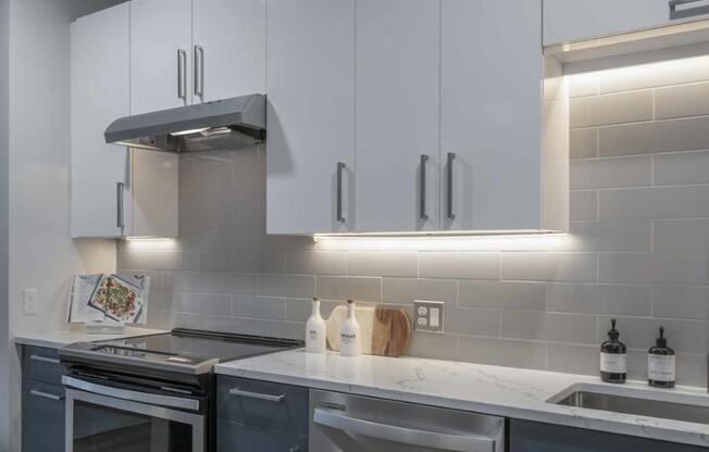 a kitchen with white cabinets and gray countertops