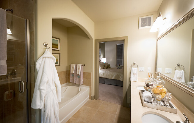 En-suite bathroom with an oval soaking tub under an arched detail, a glass shower, and a dual vanity.