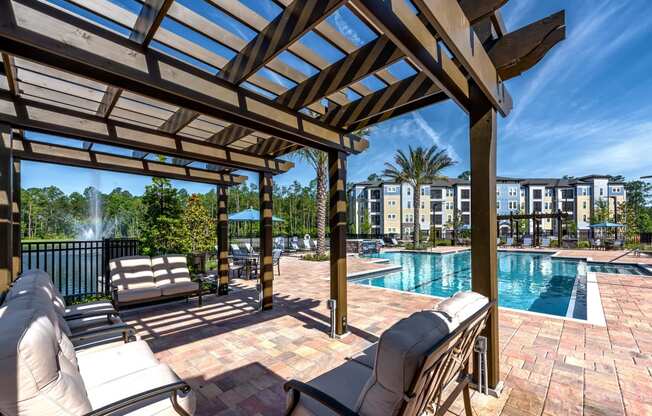 a resort style pool with lounge chairs and a pergola