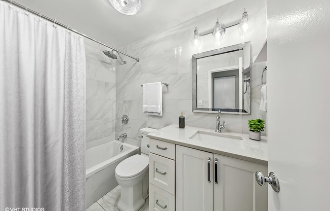 a white bathroom with a shower toilet and sink