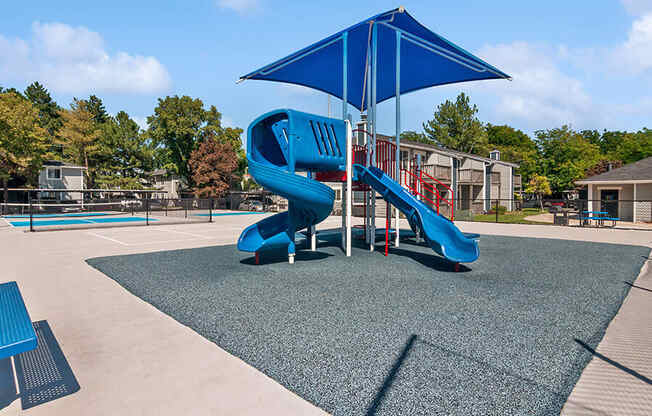 Community Playground with two Slides and Blue Canopy at Overlook Apartments located in Salt Lake City, UT.