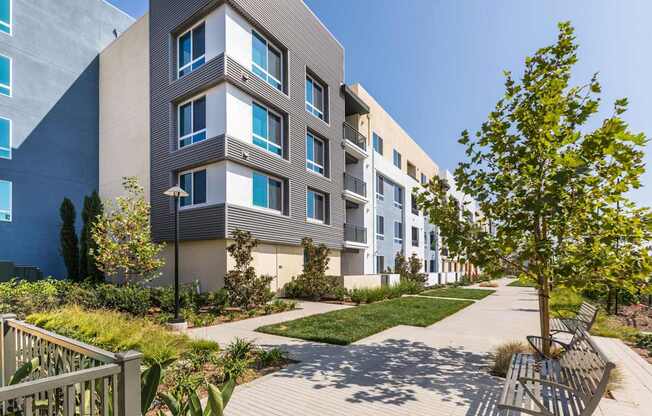 A modern apartment building with a tree in front.