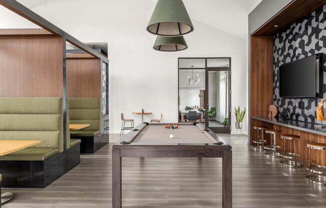 A room with a pool table and a bar area.