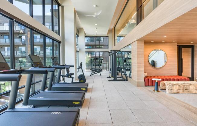 Light-filled fitness center with premium cardio and strength equipment plus relaxing lounge seating nearby.