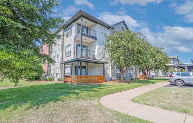 View of apartment exterior with patio and balconies and lush landscaping at Ultris Island Park in Shreveport, LA