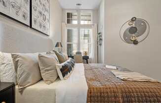 A bedroom with a bed, pillows, and a wall art.