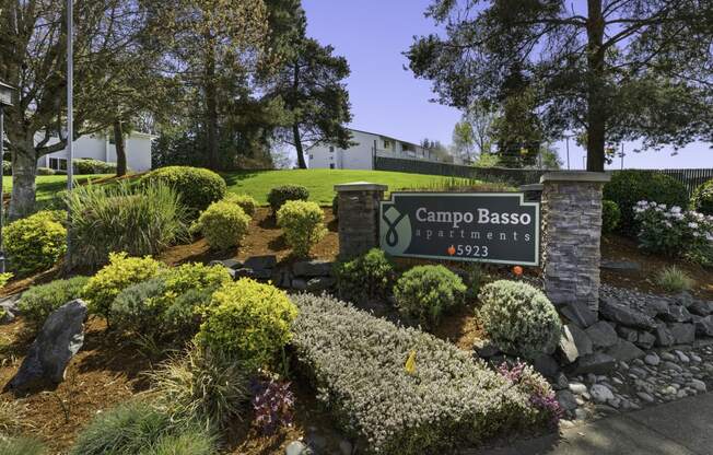 Campo Basso Property Sign with Lush Plants, Shrubs, and Bushes Under at Campo Basso Apartment Homes, Lynnwood, Washington 98087