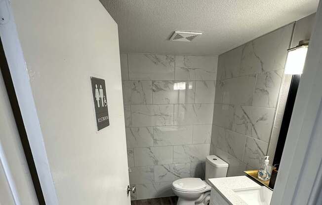 A white table with a black sticker on it in a room with a wooden wall and a ceiling fan.