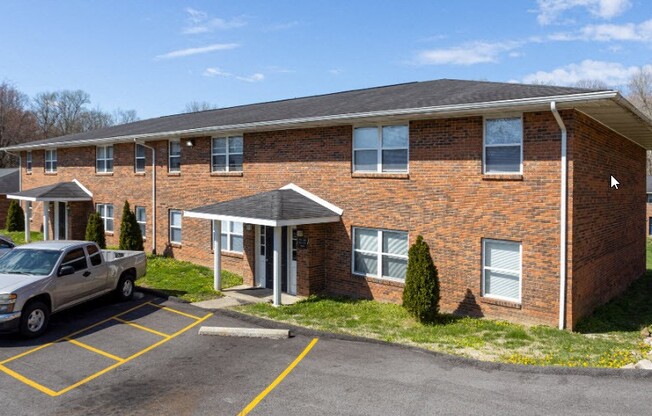 a brick building with a car parked in a parking lot