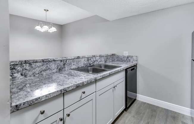 a kitchen with white cabinets and granite counter tops and a stainless steel sink