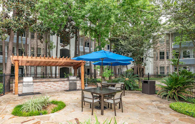 A patio with a table and chairs under a blue umbrella.