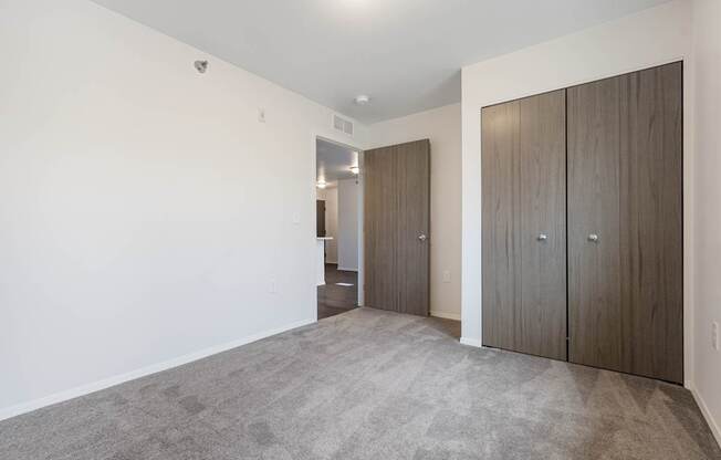 A room with a carpeted floor and two wooden doors.