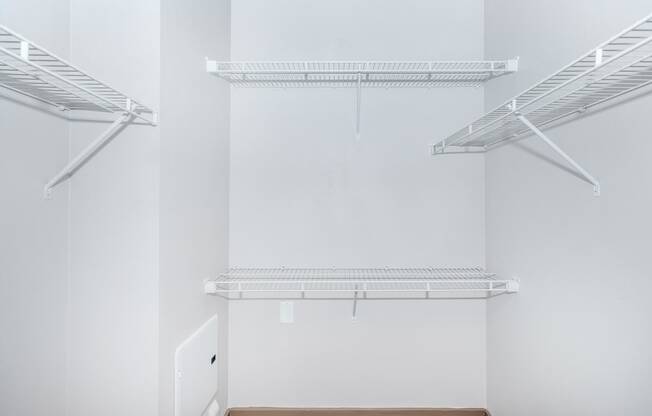 a walk in closet with white walls and white shelves