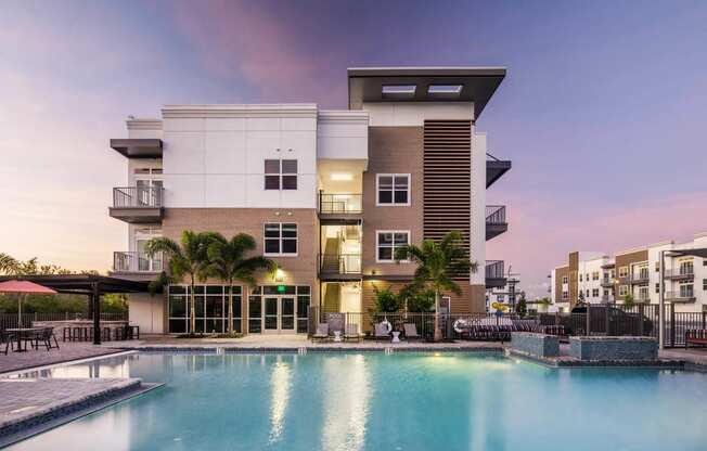 a luxury apartment building with a pool at dusk