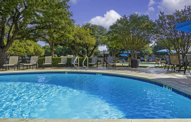 a swimming pool with chairs and umbrellas and trees