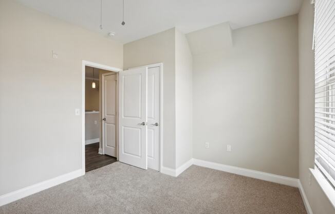 an empty bedroom with white doors and a door to a closet