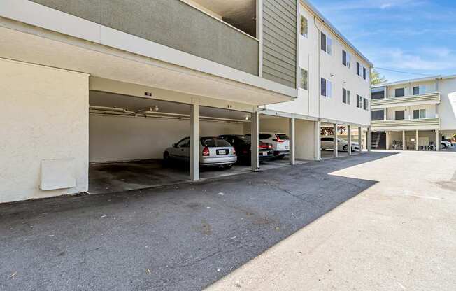 A car is parked in a garage attached to a white building.