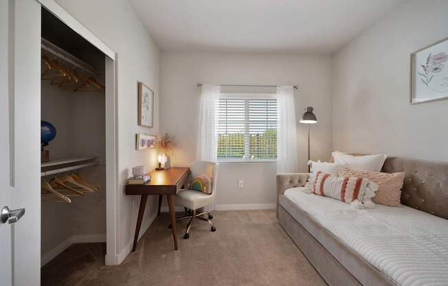 A bedroom with a bed, desk, and chair.