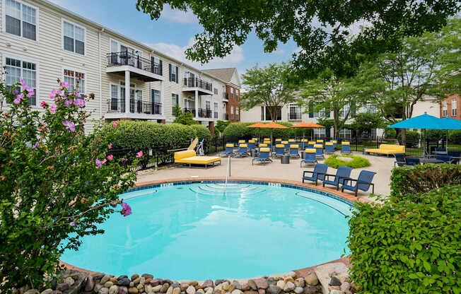 A pool surrounded by a stone wall and chairs.