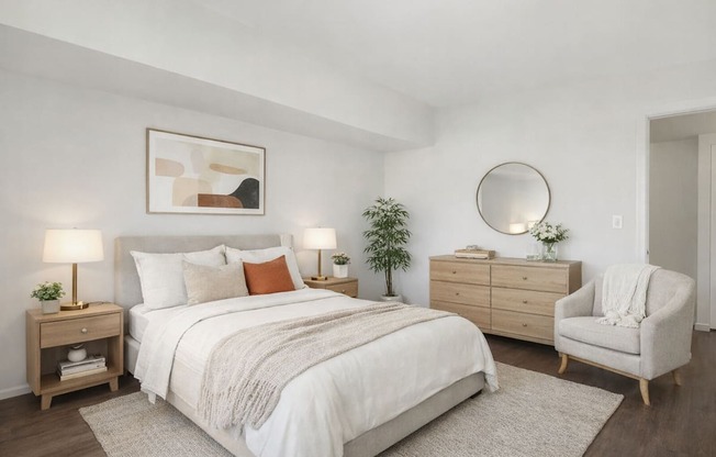 A bedroom with a large bed, a chair, and a plant.