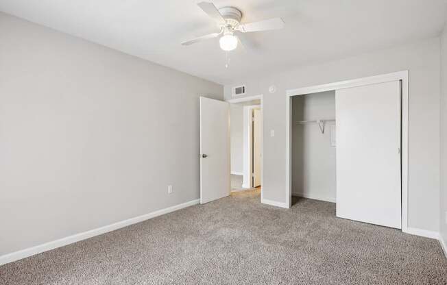A room with a ceiling fan and carpeted floor.