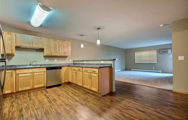 an empty kitchen and living room with wood floors and wood cabinets. Fargo, ND Urban Plains Apartments