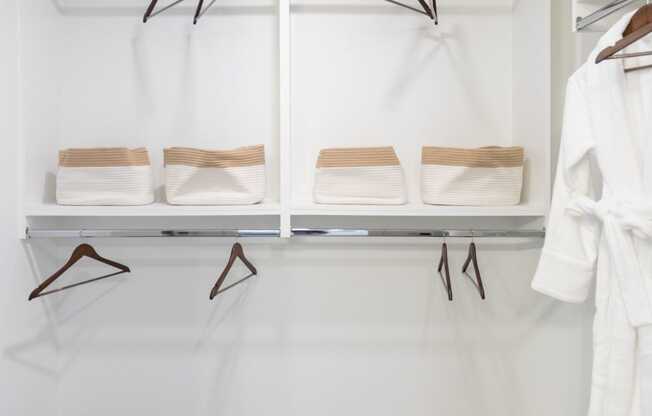 A white closet with two shelves and two hangers.